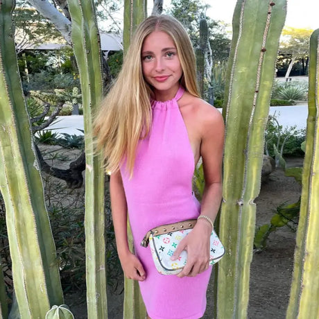 a woman in a pink dress standing next to a cactus