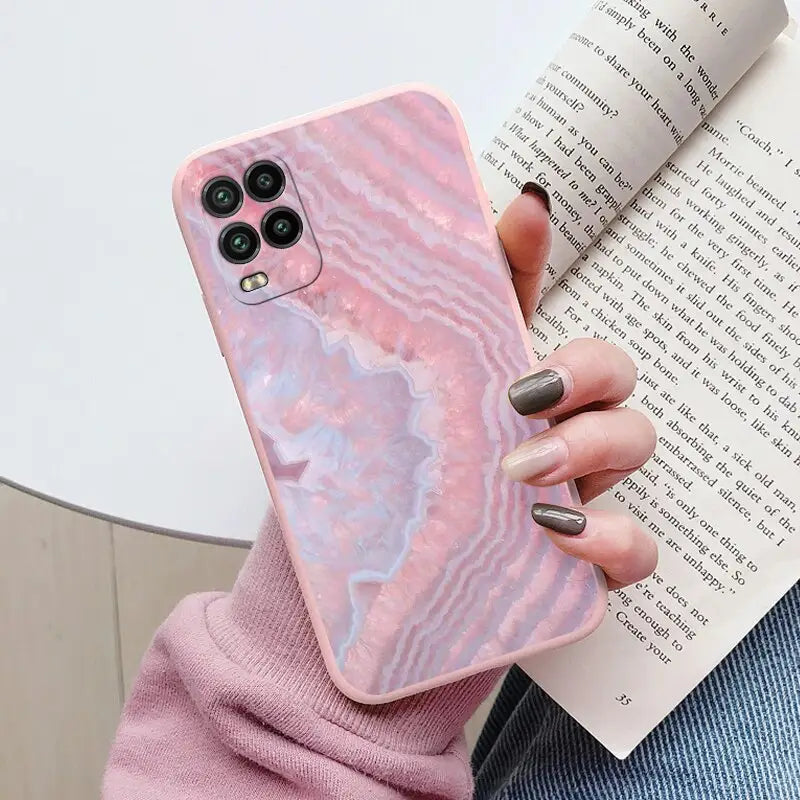 a woman holding a pink marble phone case