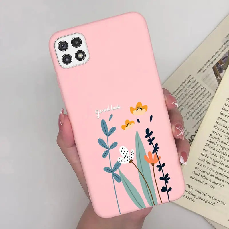 a woman holding a pink phone case with flowers on it
