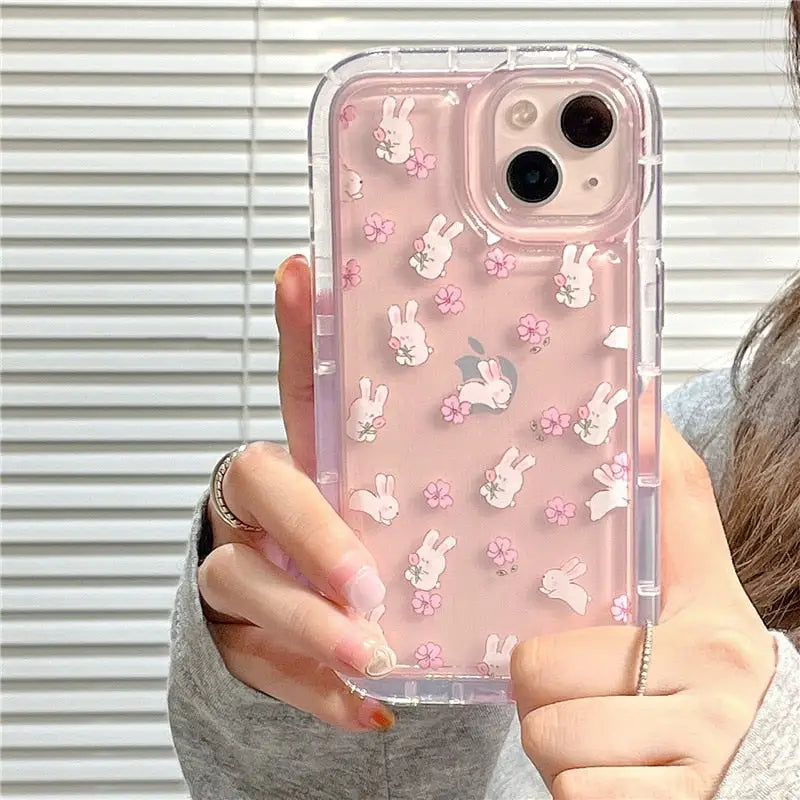 A woman holding a pink phone case with white rabbit and flowers