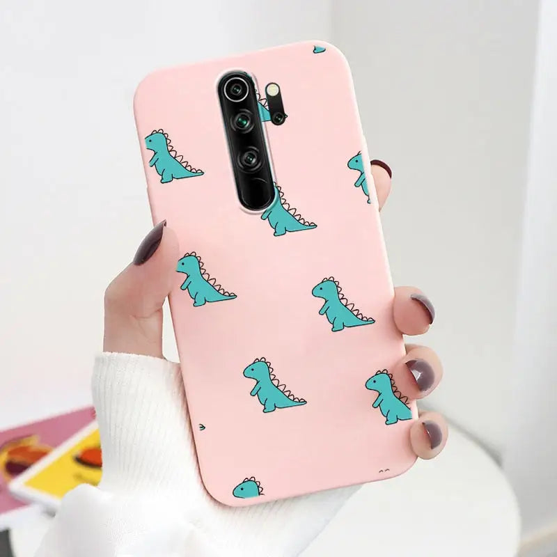 A woman holding a pink phone case with a green dinosaur pattern