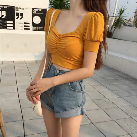 a woman wearing a yellow top and denim shorts