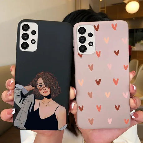 a woman holding up two iphone cases with hearts on them