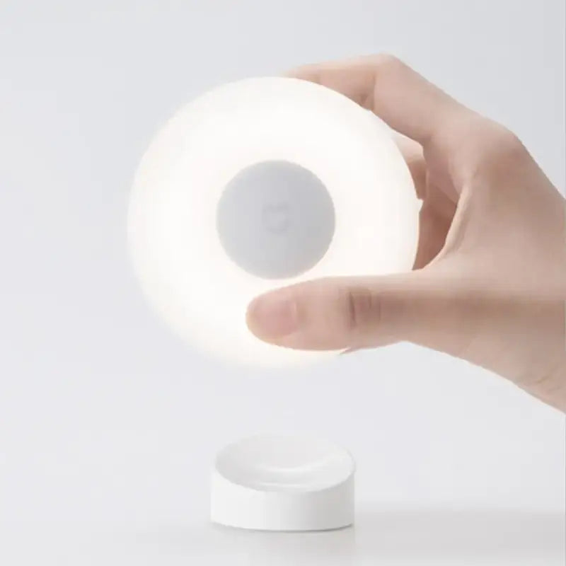a hand holding a light that is on a white surface