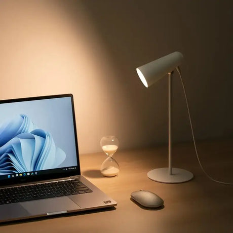 a laptop computer sitting on a desk next to a lamp