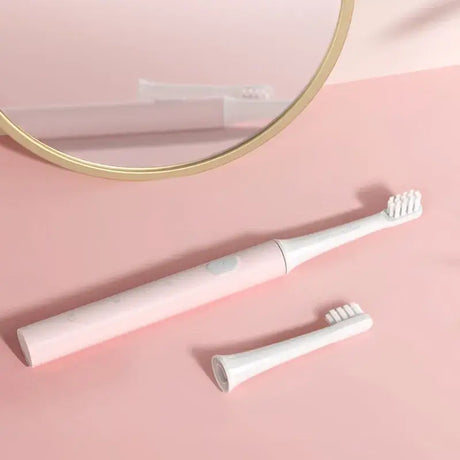 a white toothbrush and a mirror on a pink surface