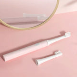 a white toothbrush and a mirror on a pink surface