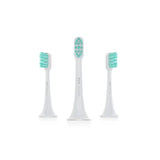 three toothbrushes with green bristles on a white background