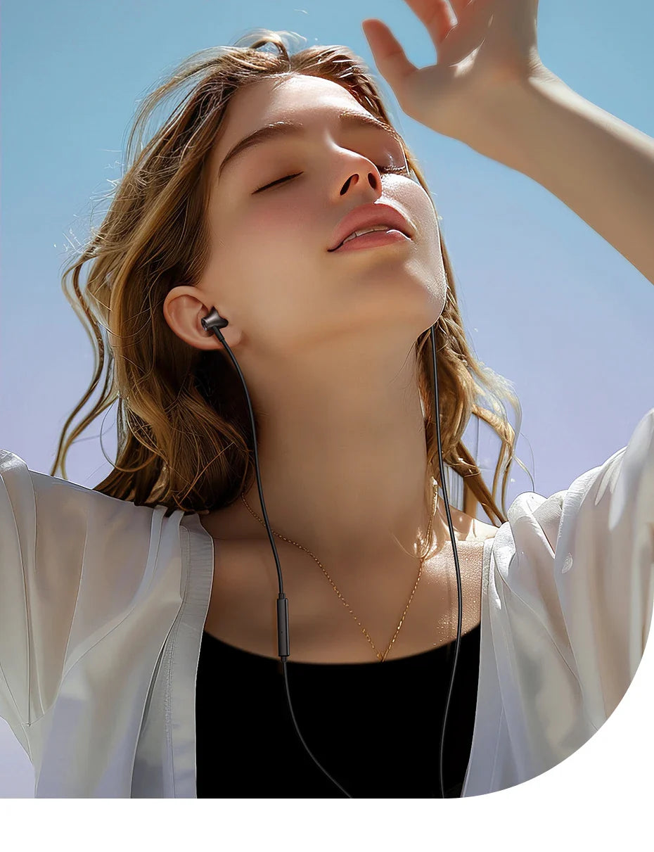 Young woman with closed eyes tilting her head back in sunlight, wearing earbuds and a white cardigan over a dark top.