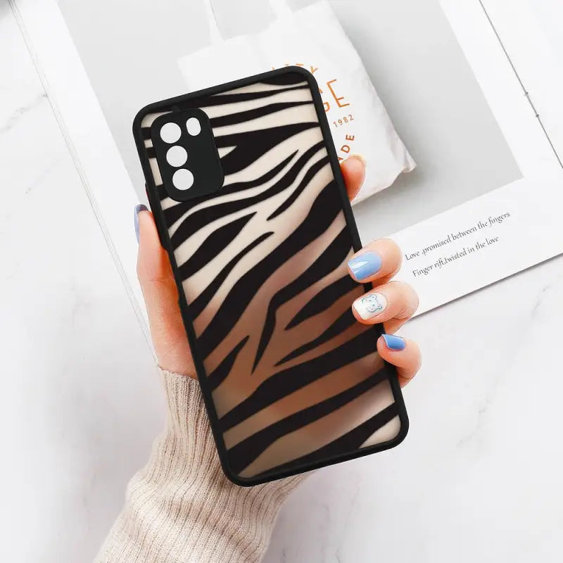a woman holding a phone case with zebra print