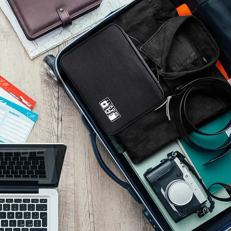 a laptop, camera, camera bag, and other items on a table