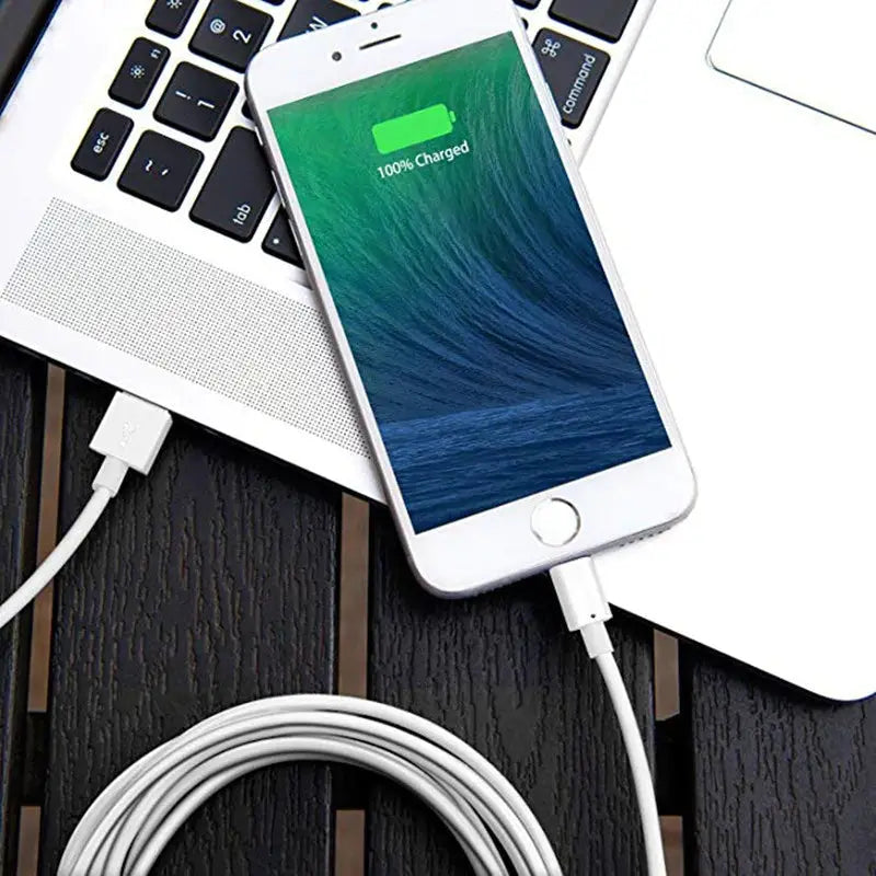an iphone charging cable next to a laptop
