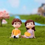 a couple sitting on the grass with a flower