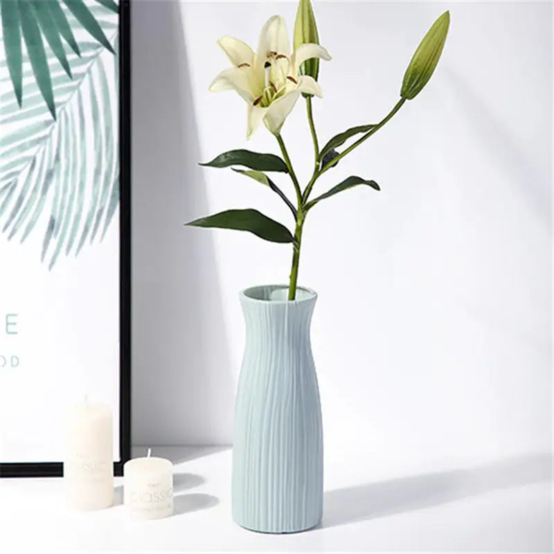 a vase with a flower in it next to a candle