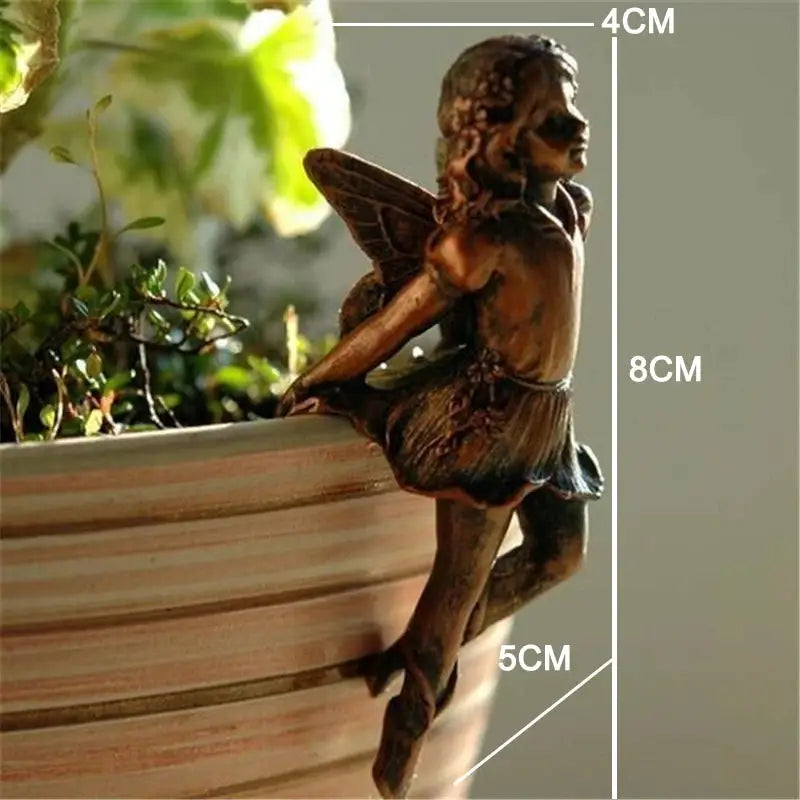 a small statue of a fairy sitting on a planter