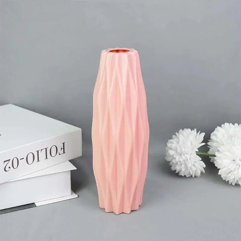a pink vase next to a white flower