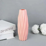 a pink vase next to a white flower