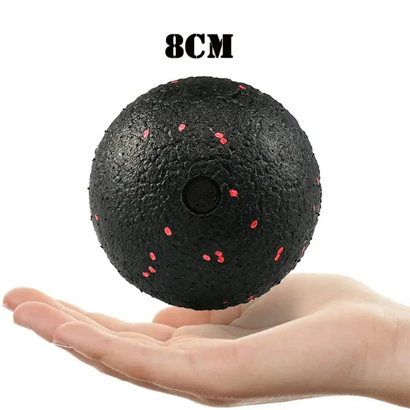 a hand holding a black ball with red dots