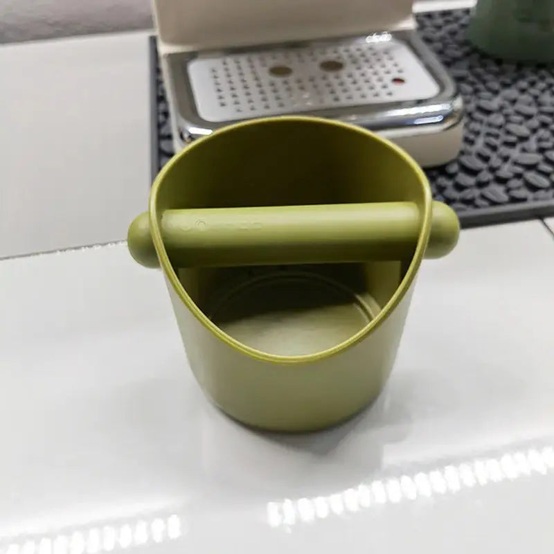 a green cup sitting on top of a white table