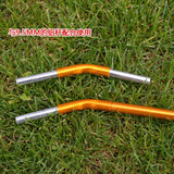 two orange aluminum handle bars laying on the grass