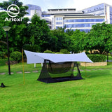 a tent in the grass with a building in the background