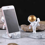 an astronaut phone holder with a gold ball