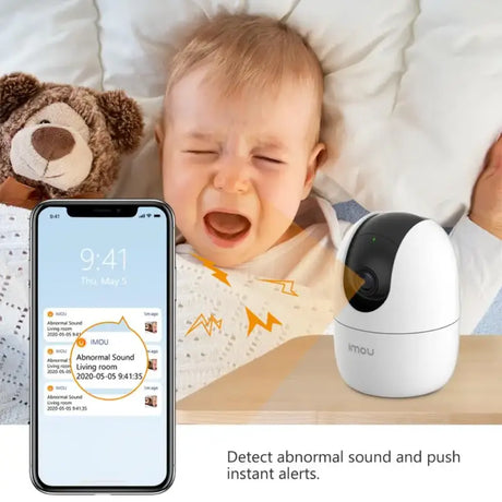 A baby is laying in bed next to a baby monitor