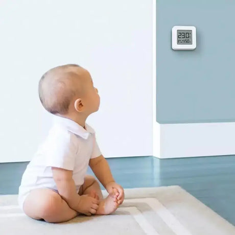 A baby sitting on the floor in front of a white wall