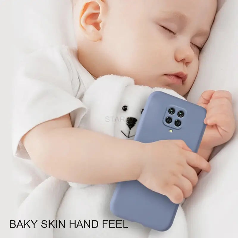 a baby sleeping on a bed with a phone