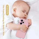 a baby sleeping on a bed with a pink phone case