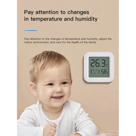 A baby is smiling while he is holding a thermometer