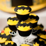 batman cupcakes are displayed on a glass plate with a batman cake