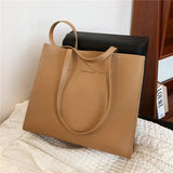 a beige leather tote bag with a black leather handle