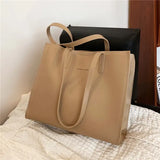 a beige leather tote bag with a black leather handle