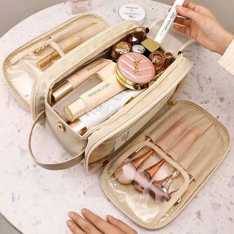 Beige makeup bag with multiple compartments containing various cosmetic products and tools.