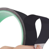 a hand holding a black tape with green tape