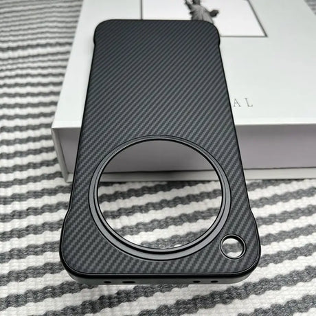Black carbon fiber phone case with a large circular camera cutout and a smaller circular cutout for a button or sensor.