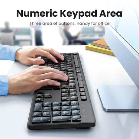 Black computer keyboard with a numeric keypad being used by hands in a blue sleeve.