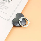 a black heart shaped ring on top of a white sheet