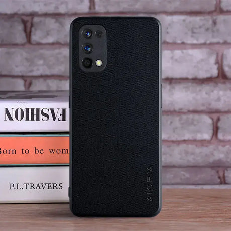 The back of a black iphone case sitting on top of a stack of books