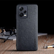 the back of a black leather case with a pen and glasses on it