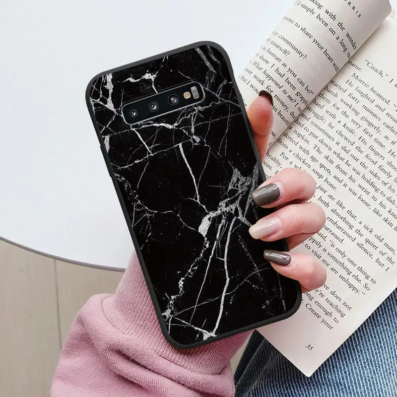 a woman holding a book and a black marble phone case