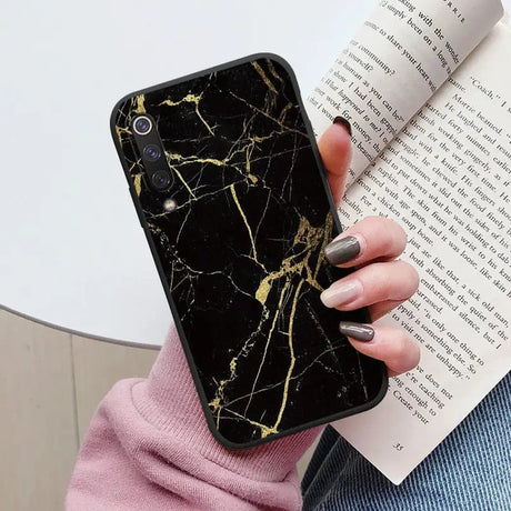 a woman holding a book and a black marble phone case