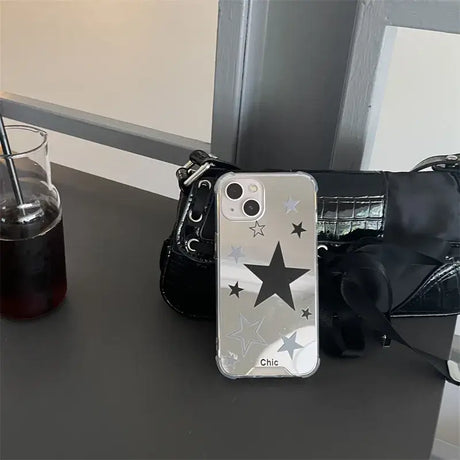 There is a black purse and a silver star phone case on a table