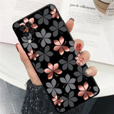 a woman holding a phone case with a black and pink flower design