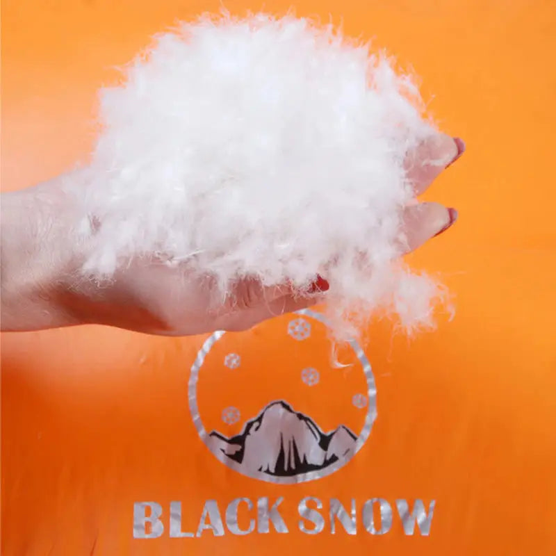 a hand holding a white fluffy ball in front of an orange background
