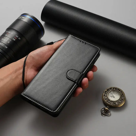 Someone holding a black wallet with a camera and a lens