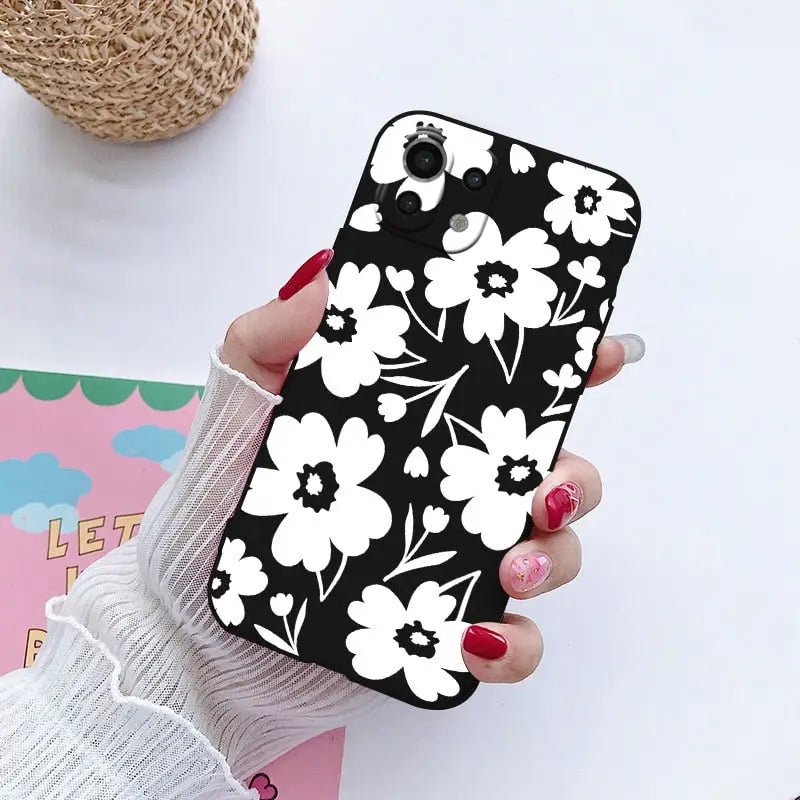 a woman holding a phone case with white flowers on it