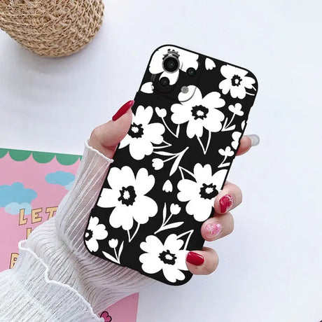 a woman holding a phone case with white flowers on it