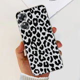 a woman holding a phone case with a black and white leopard print